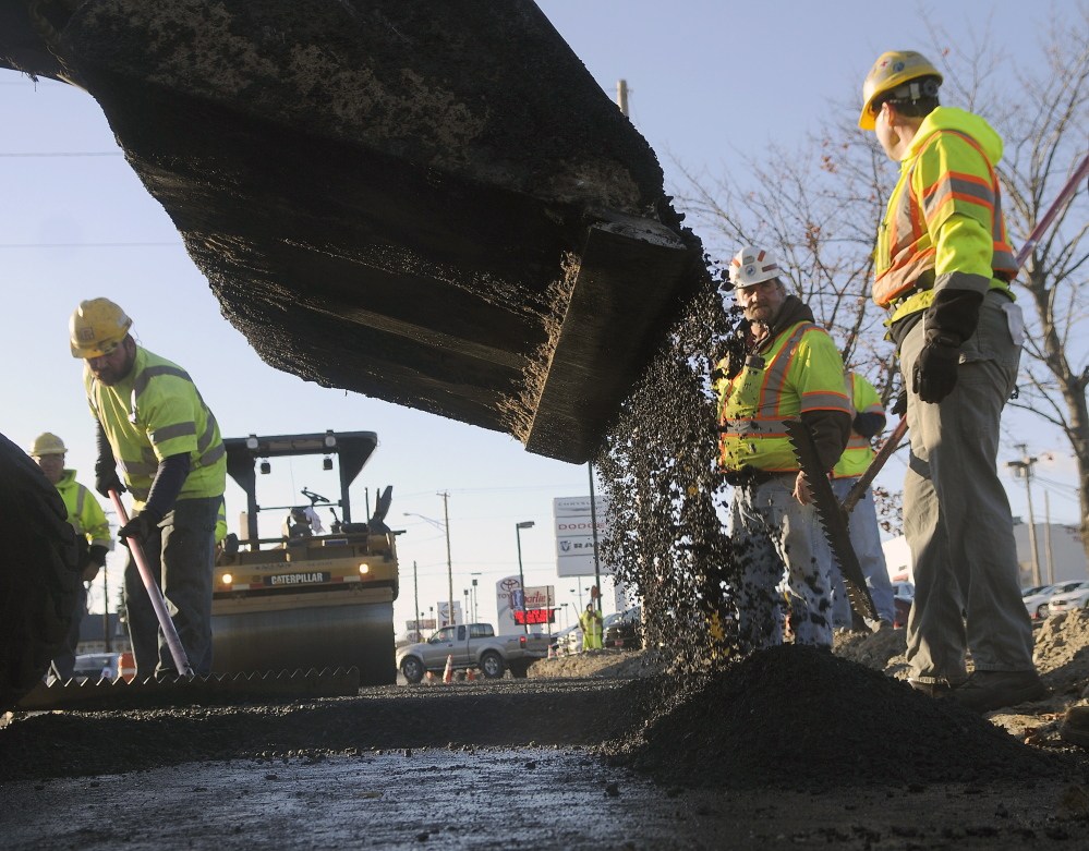 Pike Industries and Maine Department of Transportation employees pave Western Avenue in Augusta on Monday.