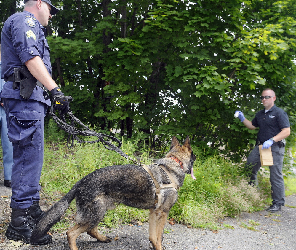 In this August file photo, Gardiner Police Detective Mike Durham collects a pill bottle that State Police Sgt. Mathew Casavant and his dog discovered a couple blocks away from the Rite Aid pharmacy that was robbed in Gardiner.
