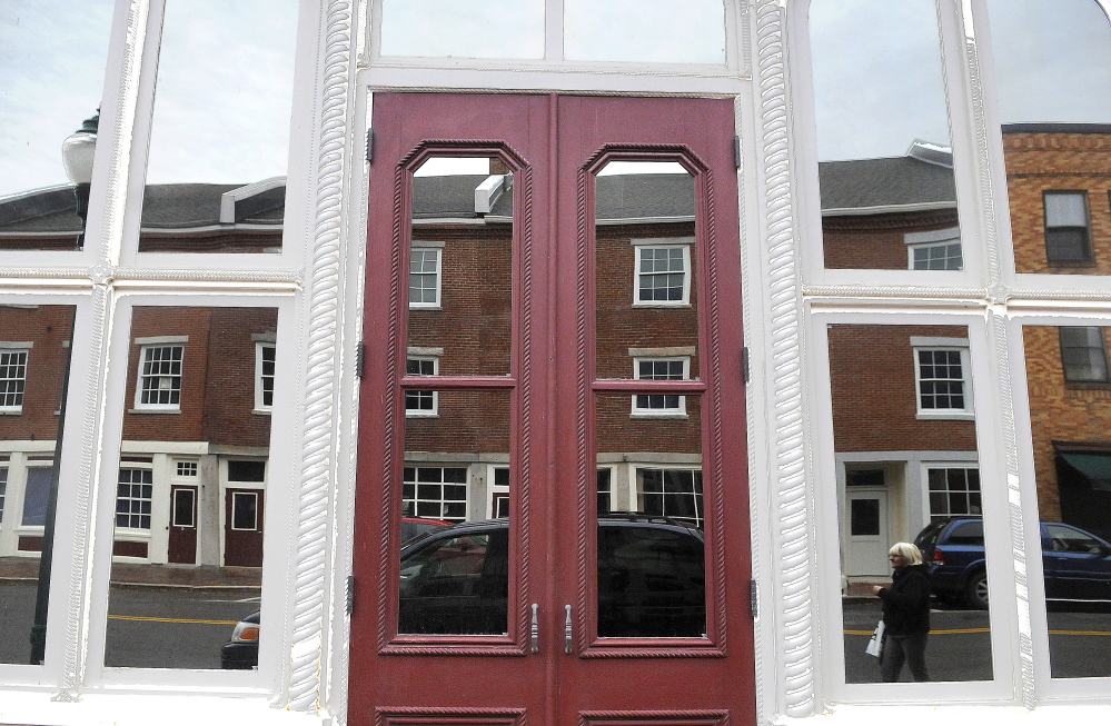 A shopper is reflected in a window in downtown Gardiner on Tuesday. Maine Preservation released its annual list of the state’s most endangered historic properties Tuesday, including downtown Gardiner on its list because of concerns over flood insurance.
