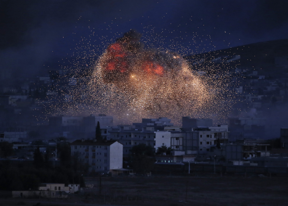 In this Monday, Oct. 20, file photo, thick smoke and flames from an airstrike by the U.S.-led coalition rise in Kobani, Syria, as seen from a hilltop on the outskirts of Suruc, at the Turkey-Syria border.