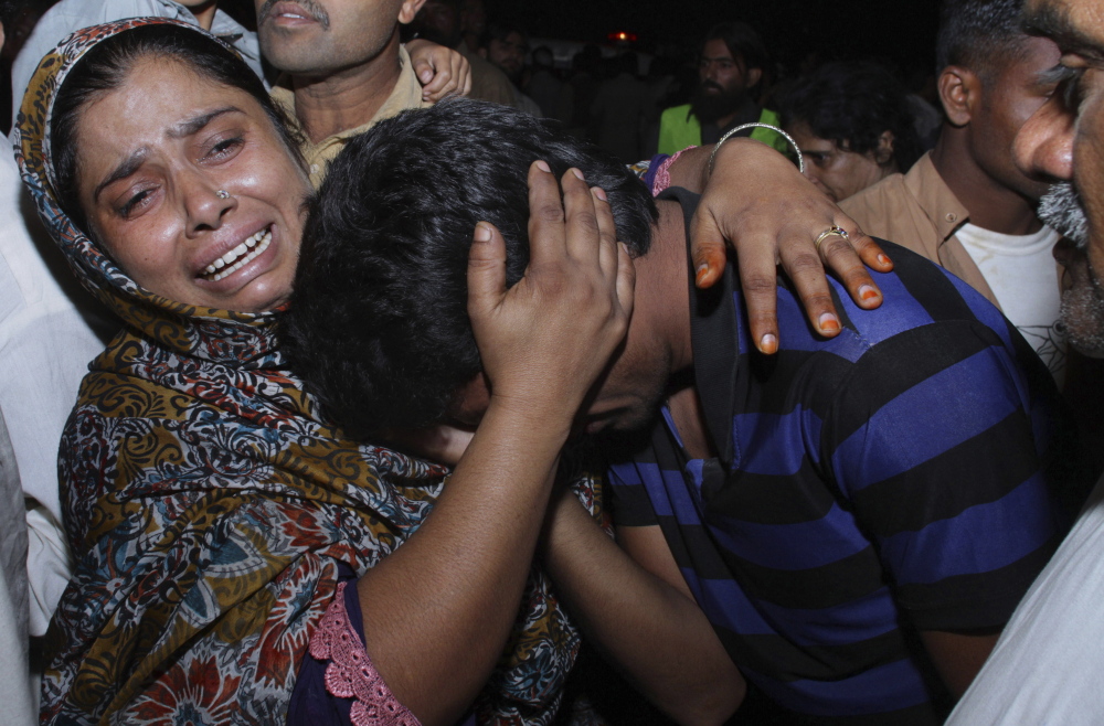 A woman at a hospital in Lahore, Pakistan, comforts a man mourning for their relative killed in a suicide bomb explosion near a Pakistani paramilitary checkpoint Sunday.