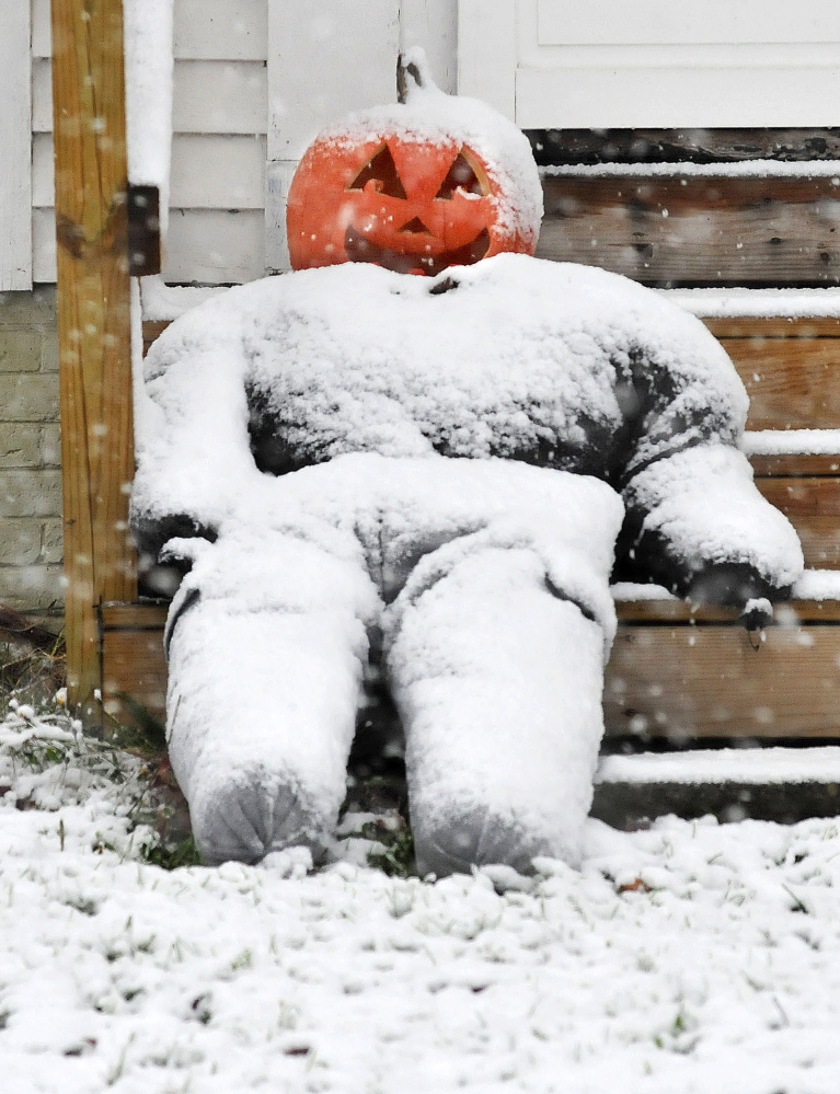 A carved Halloween pumpkin still smiles as snow accumulates on it in Waterville on a snowy Sunday.