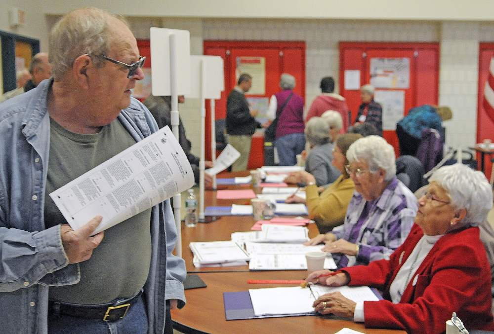 Andy Struck clutches ballots Tuesday while looking for a spot to vote at the polls in Winthrop. Communities across Kennebec County reported heavy voter turnout.