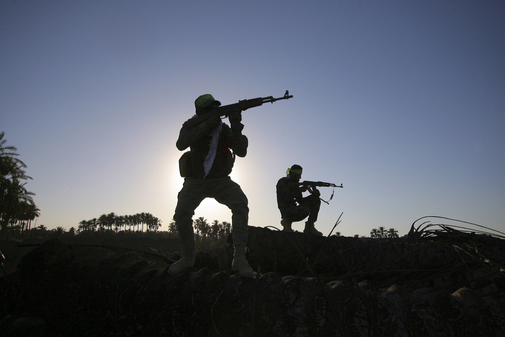 In this Tuesday, Oct . 7,  2014 file photo, Iraqi Shiite militiamen aim their weapons during clashes with militants from the Islamic State group, in Jurf al-Sakhar, about 43 miles (70 kilometers) southwest of Baghdad, Iraq.