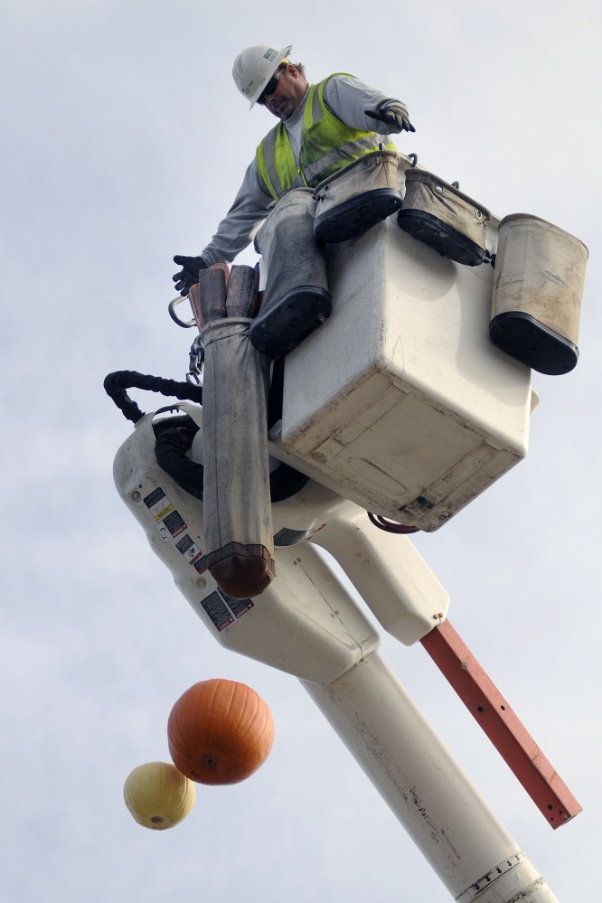 Central Maine Power lineman Greg Fortin drops pumpkins onto the pavement at Maranacook Community Middle School in Readfield on Monday. Students were learning about Newton’s laws of physics for a class.