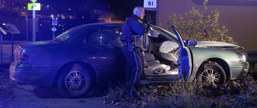Augusta Police Officer Scott Taylor secures a car after the operator allegedly attempted to elude police before crashing on Cony Circle in Augusta on Saturday. The driver fleeing police sped down Western Avenue, drove straight across Memorial Circle, crashed at the Cony Circle, and led police on a brief foot chase before being arrested, according to Augusta Police.