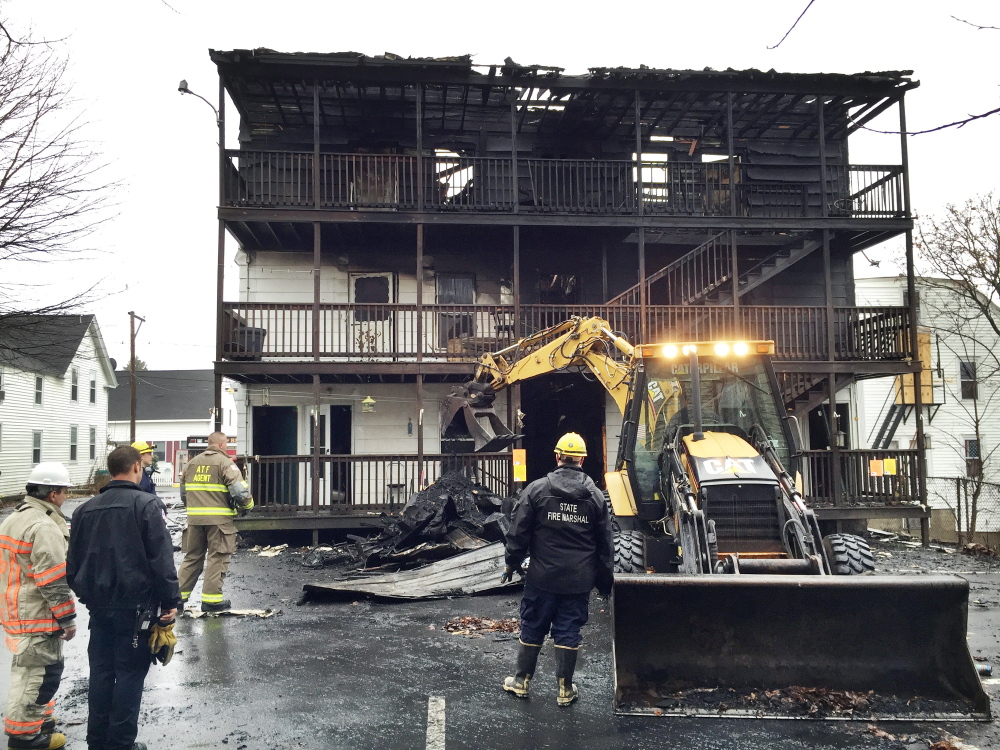 Investigators with the State Fire Marshal’s Office as well as the federal Bureau of Alcohol, Tobacco, Firearms and Explosives wait Monday for a backhoe to spread debris that was pulled out from inside the first floor at 25 Green St. in Biddeford. Officials had not determined if the building was safe to enter, so they began their investigation by examining debris.