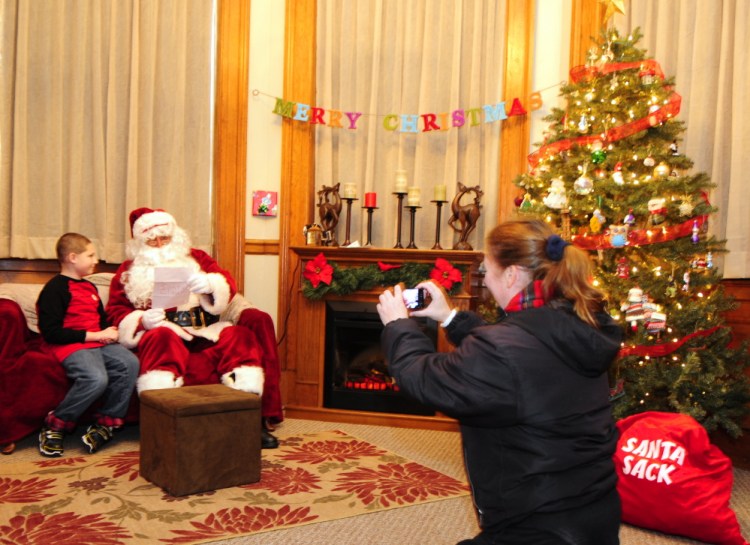 Patrick DeMaria, 10 of Augusta, gives a letter to Santa Claus as Patricia DeMaria takes a picture Saturday in downtown Augusta. A room full of activities with elves was put on by Wellness Management, Stacy’s Hallmark & The Looke at Stacy’s, and Hallmark for ME before children got to meet Santa and Mrs. Claus.