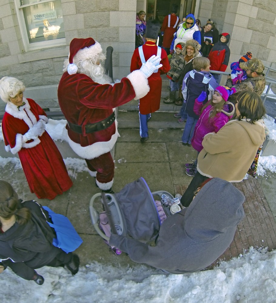 Mrs. Claus, left, and Santa Claus are led by toy soldiers Saturday into the Olde Federal Building in downtown Augusta. A tree lighting and fireworks occurred later in the day.
