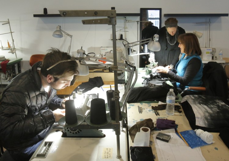 Evan Michael, left, Roxi Suger, standing, and Denise Laverriere work in the new production facility of Angelrox, a clothing line that Suger produces in the Pepperell Center in Biddeford. The line is sold in about 300 stores nationwide. Gregory Rec/Staff Photographer