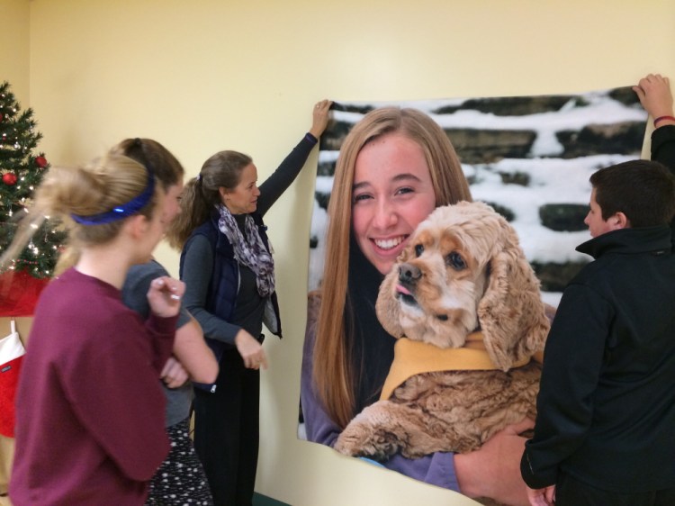 Volunteers from the Mount Merici Young Alums decorate the Humane Society Waterville Area Friday in memory of Cassidy Charette, of Oakland, whose picture they hung along with Christmas decorations. Charette was a volunteer at the humane society and died in a hayride accident in October. On the left are Molly Calkins, Ella Moore and parent Stephanie Calkins. The students are volunteering for Saturday’s annual open house