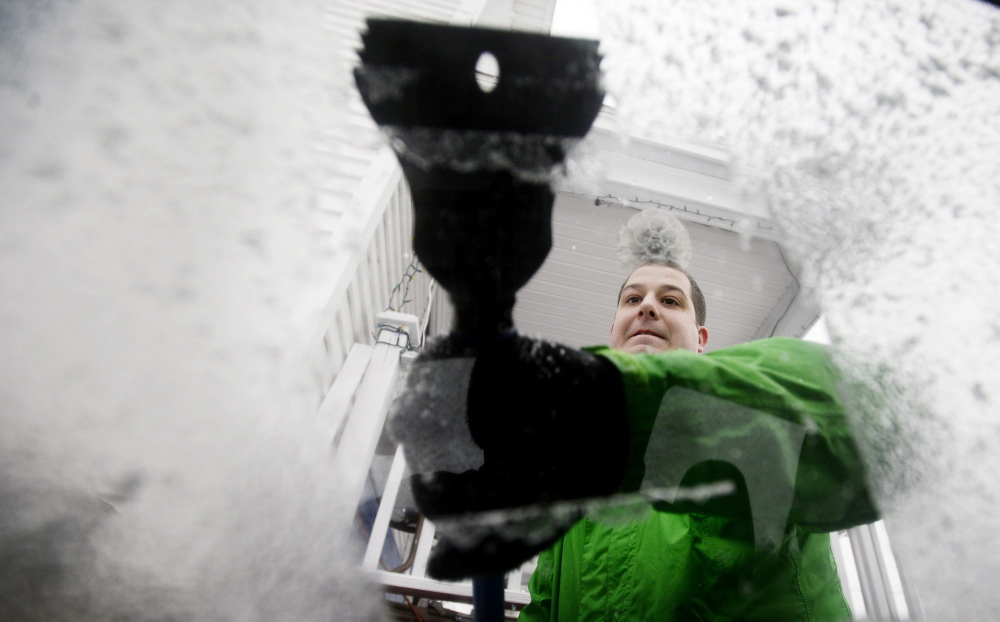 Adam Lascelle of South Portland scrapes ice off his car window during Tuesday’s storm. High winds accompanied precipitation that included rain, sleet and snow.