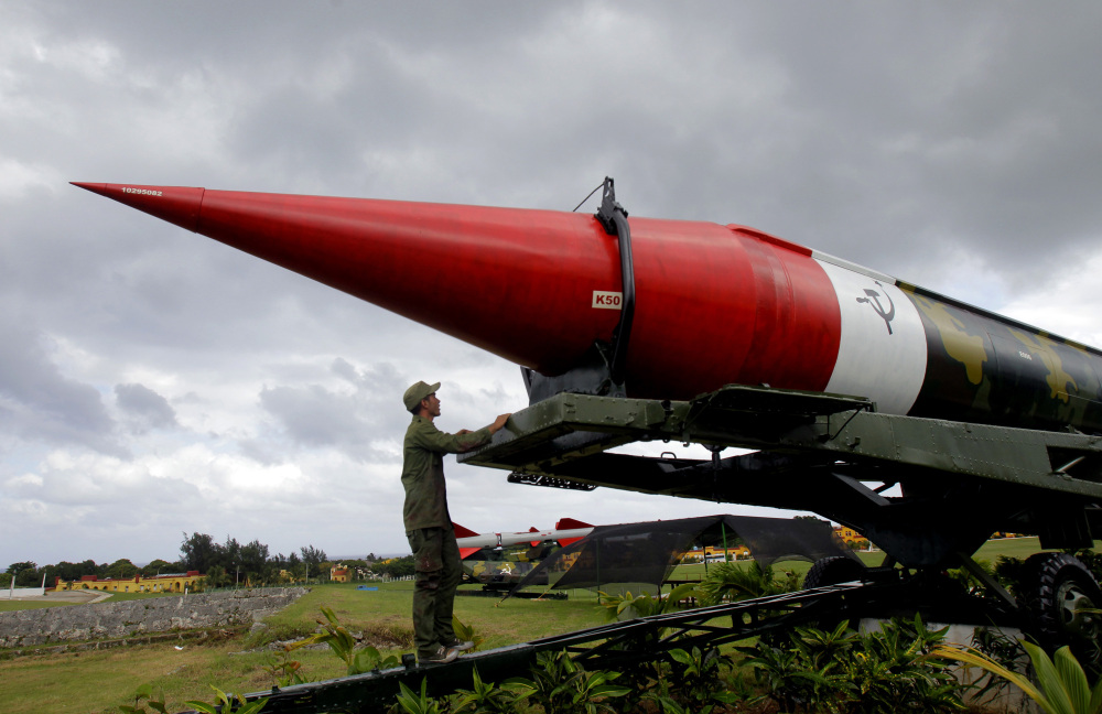 FILE - In this Oct. 13, 2012 file photo, a soldier pauses to look at the outer casing of an old empty Soviet missile on exhibit as he works to paint it at the military complex Morro Cabana which is open to tourists in Havana, Cuba. The world stood at the brink of Armageddon for 13 days in October 1962 when President John F. Kennedy drew a symbolic line in the Atlantic and warned of dire consequences if Soviet Premier Nikita Khrushchev dared to cross it. On Wednesday, Dec. 17, 2014, the U.S. and Cuba agreed to re-establish diplomatic relations and open economic and travel ties, marking a historic shift in U.S. policy toward the communist island after a half-century of enmity dating back to the Cold War. (AP Photo/Ismael Francisco, Cubadebate, File)