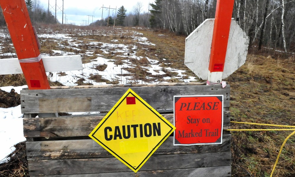 Signs along a snowmobile trail nearly barren of snow warn riders of poor conditions beside the Skowhegan Sno-Hawks club house in Skowhegan. There was no sight of snowmobilers out riding on the unseasonably warm Sunday.