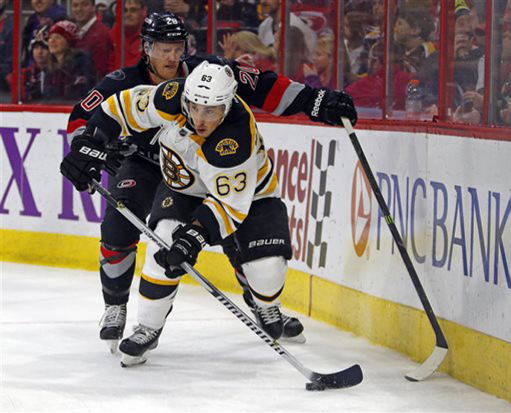 Boston Bruins’ Brad Marchand battles with Carolina’s Riley Nash (20) in Sunday’s game at Raleigh, N.C. The Hurricanes won 2-1 in a shootout.