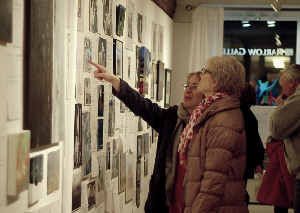 Judy Feinstein, a Kennebec Valley Art Association member and volunteer, points to a piece of art displayed in the gallery.