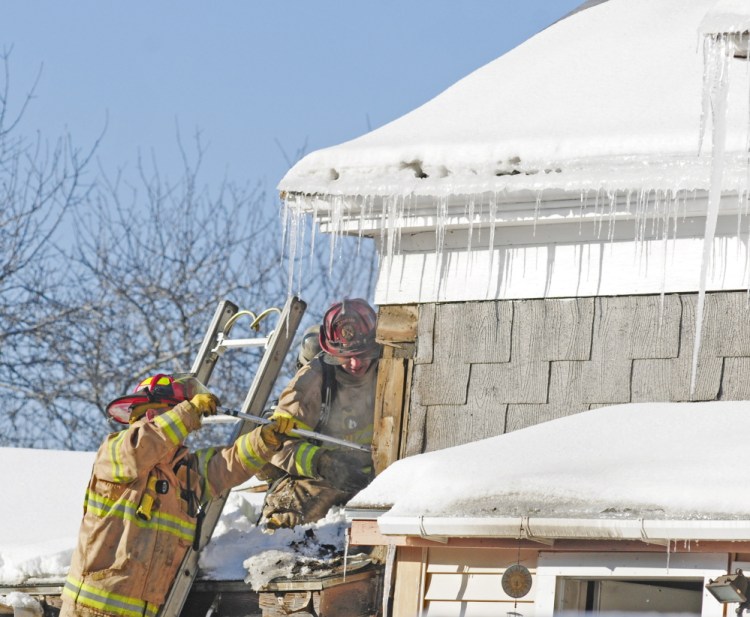 Staff photo by Joe Phelan
Firefighters work to find hot spots after extinguishing a fire on Friday on Main Street in Richmond.