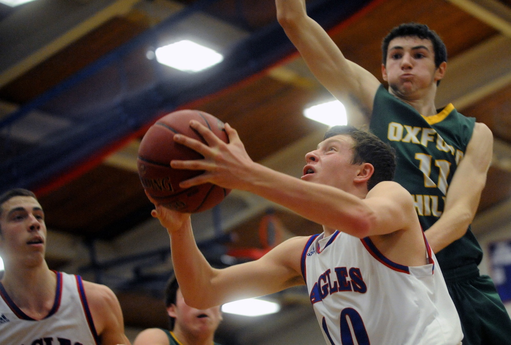 Staff photo by Michael G. Seamans 
 Messalosnkee High School's Nathan Violette, front, drives to the basket as Oxford Hills' Tyus Ripley defends.