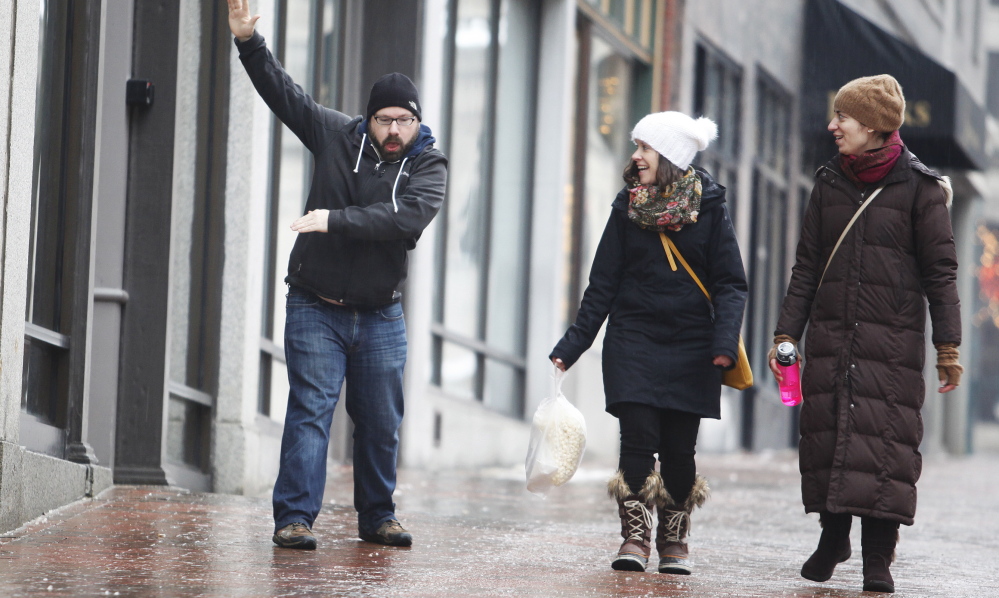 Katherine Jacobs, center, and Whitney Wotkyns watch as Tony Wilbur slips and slides on the icy bricks in Portland on Sunday.