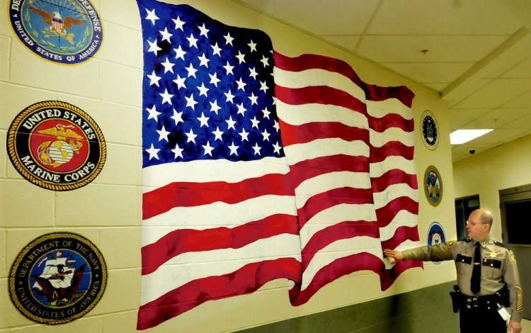 Somerset County Sheriff Dale Lancaster explains how inmate and artist Michael Halle painted an American flag that appears to wave on a wall inside the Somerset County Jail in East Madison on Thursday.
