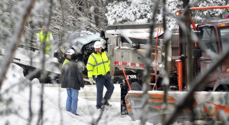 A tow truck driver in the background pulls a vehicle onto a flatbed wrecker at the accident scene on Interstate 95 just south of exit 112 on Thursday in Augusta.