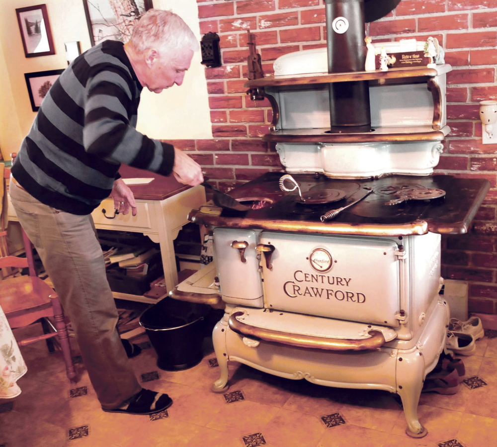 John Keister adds small pieces of nut coal into his stove at his Norridgewock home on Thursday.