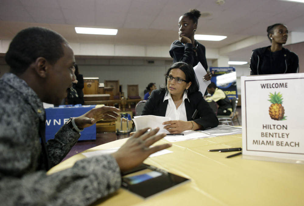 In this Friday, Jan. 23, 2015 photo, Debbie Ramsawak, Director of Operations at the Hilton Bentley Miami Beach hotel, center, seated, talks with job applicant Zikey Cook, 24, left, during a job fair at the Hospitality Institute, in Miami.