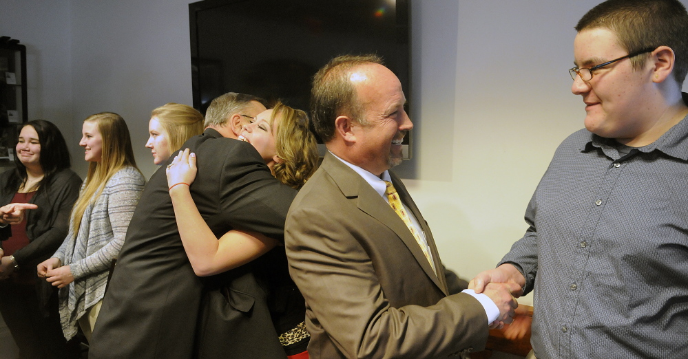 AT&T executive Owen Smith shakes hands Tuesday with Cony High School junior Noah Patenaude as Gov. Paul LePage hugs Ann Veilleux following the announcement at the State House of a grant worth $200,000 to expand the Jobs for Maine Graduates program at Cony. Veilleux, 21, cited the program as the reason for her success after a rough adolescence in Vassalboro.