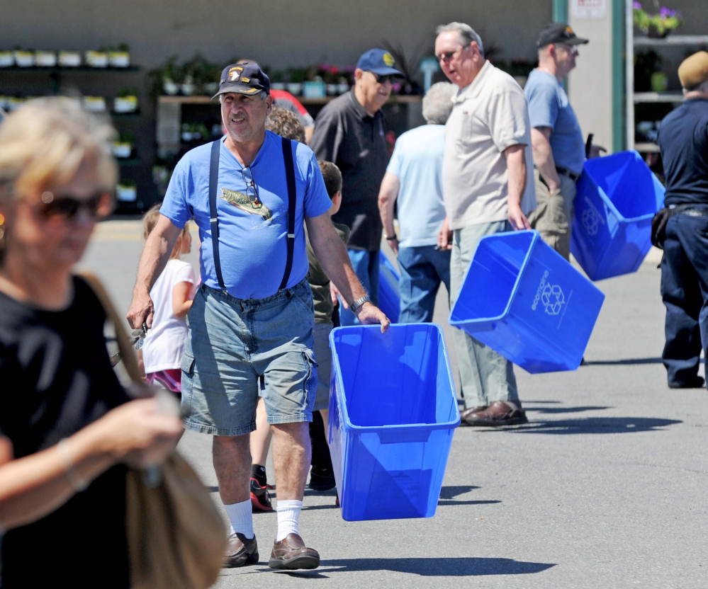 People return to their vehicles with free recycling bins from Ecomaine at Elm Plaza in Waterville in June 2014. Ecomaine is proposing to work with Augusta on a pilot recycling program.
