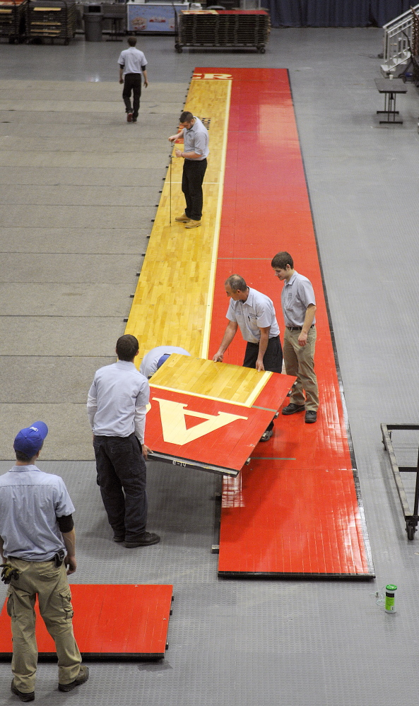 Augusta Civic Center employees put down the basketball court Tuesday. The civic center is replacing the high school floor with a college floor for the high school basketball tournament.