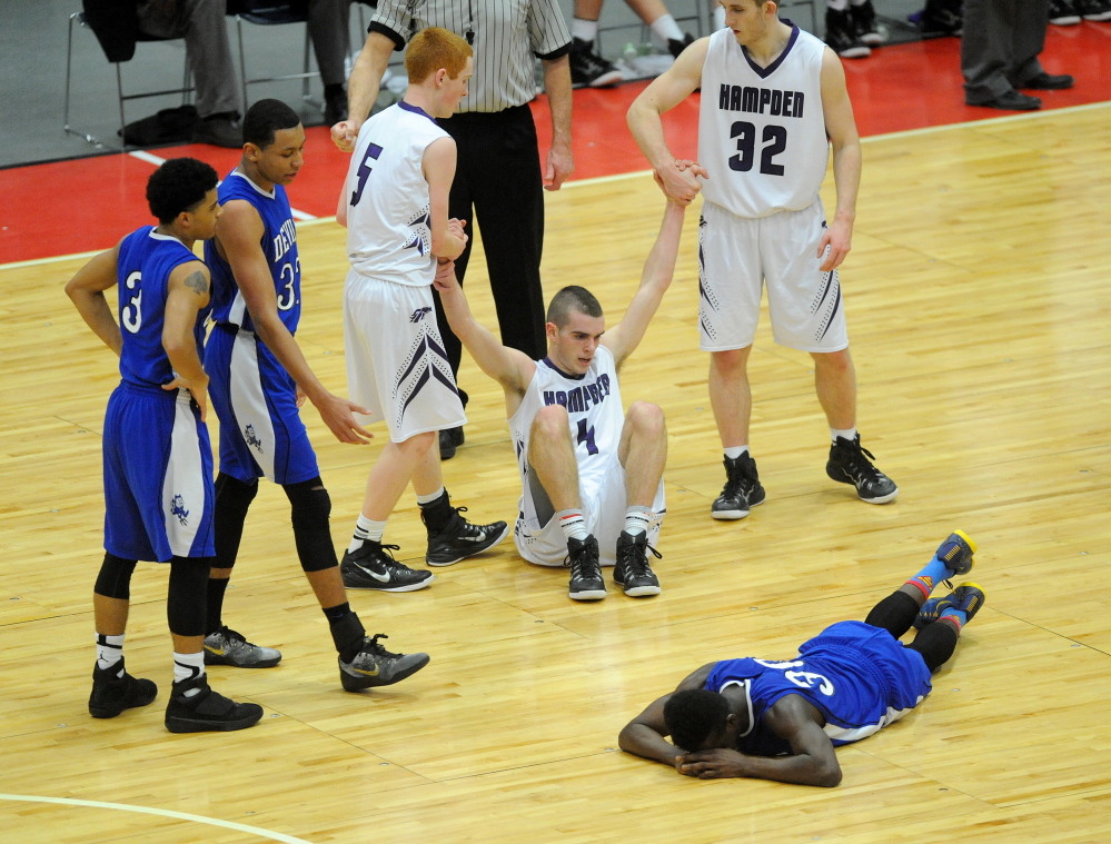 Quintarian Brown, 30, lies on the court after fouling Hampden Academy’s Nick Gilpin, 4, late in the fourth quarter of the Eastern A championship game Saturday afternoon.