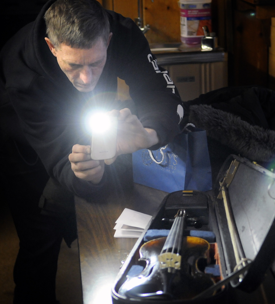 Mark Simpson photographs a violin that the Badershall family of Augusta arranged to get restored. The instrument was returned to the family Tuesday at American Legion Fitzgerald-Cummings Post 2 in Augusta. The instrument was made in 1850, according to a label found inside the body.