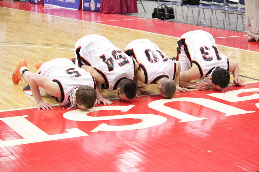 Forest Hills seniors, from left, Ryan Petrin, Tanner Daigle, Brandon Ouellette and Matt Turner, kiss the Augusta Civic Center floor after the Tigers won the Western D championship last weekend. Forest Hills has made it a tradition to kiss the Civic Center floor after it wins a title.