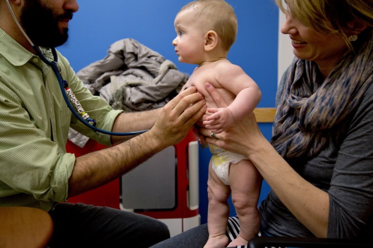 Dr. Andrew Tenenbaum of InterMed Pediatric Care in South Portland examines 6-month-old Alexander Hickey, held by his mother, Bethany, of South Portland, during a doctor’s visit Thursday that included a meningitis vaccination for the baby. A recent outbreak of measles in California “has made me extra sure to be current on everything,” Hickey said. Gabe Souza/Staff Photographer