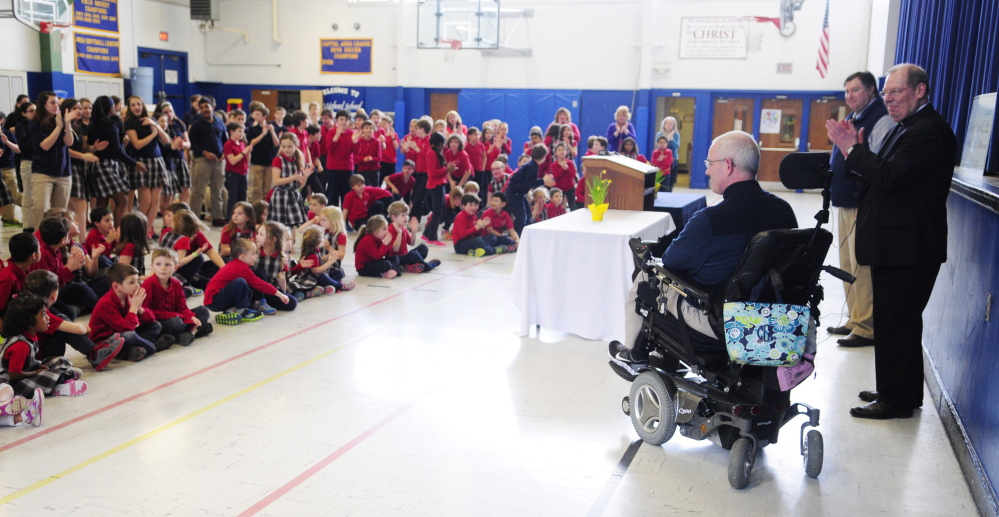 Augusta Police Chief Robert Gregoire receives a standing ovation Wednesday from students in the St. Michael School gymnasium in Augusta.