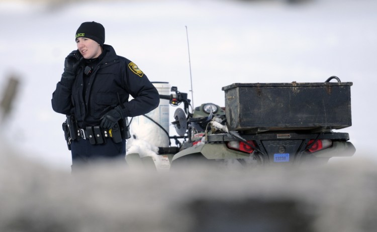 Augusta Police Officer Laura Drouin stands next to an all-terrain vehicle on Togus Pond. The body of the man who was operating the ATV was found on the pond about a hundred yards from Route 105 in Augusta.