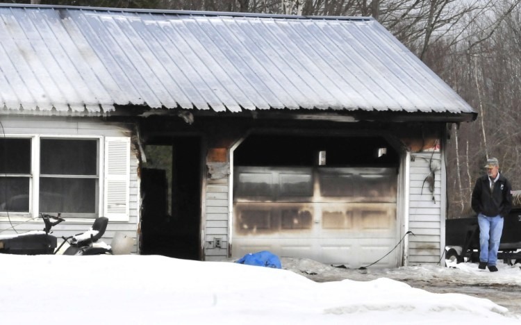 John Couture  surveys the damage  caused by a Monday evening  fire to the home of his neighbor, Dana Nadeau, on Dinsmore Road in Sidney.  Nadeau suffered burns while siphoning gas that was ignited by a kerosene heater, fire officials said. The home was destroyed.