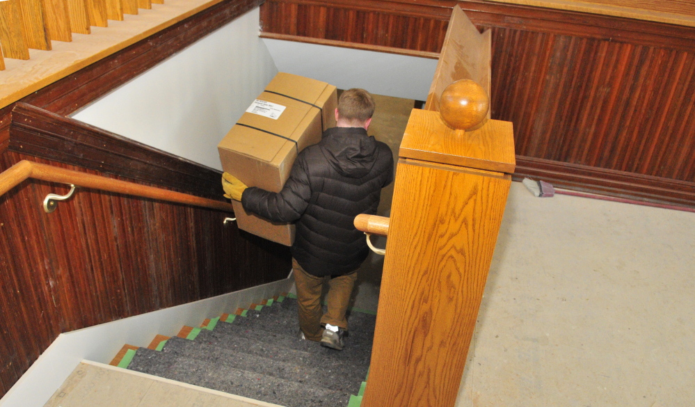 Library director Richard Fortin carries equipment to the basement of the new addition under construction at the C.M. Bailey Library in Winthrop on Thursday. The wainscoting and trim on the walls in the photo was repurposed from the old Masonic Temple that was demolished to make room for the new addition.