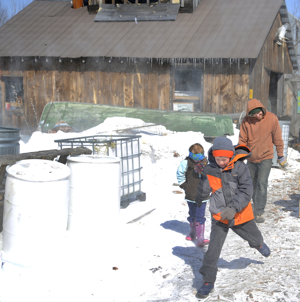 Jaxon August, 8, leads his sister, Anna, 6, and father Ryan through gusts of wind Sunday outside Mike’s Maple House in Winthrop. The sugar shack hosted the public on Maine Maple  Sunday.