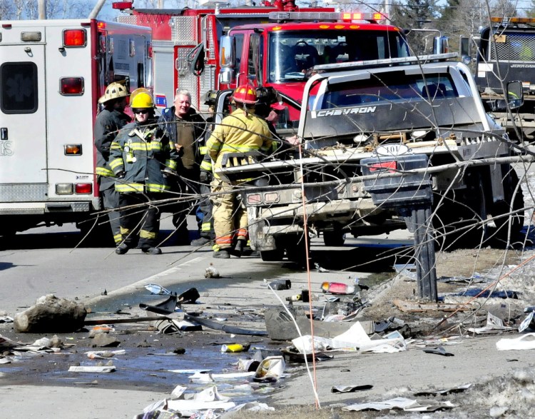 Firefighters and onlookers talk on Tuesday as police reconstruct the scene of the accident on U.S. Route 201 in Madison.