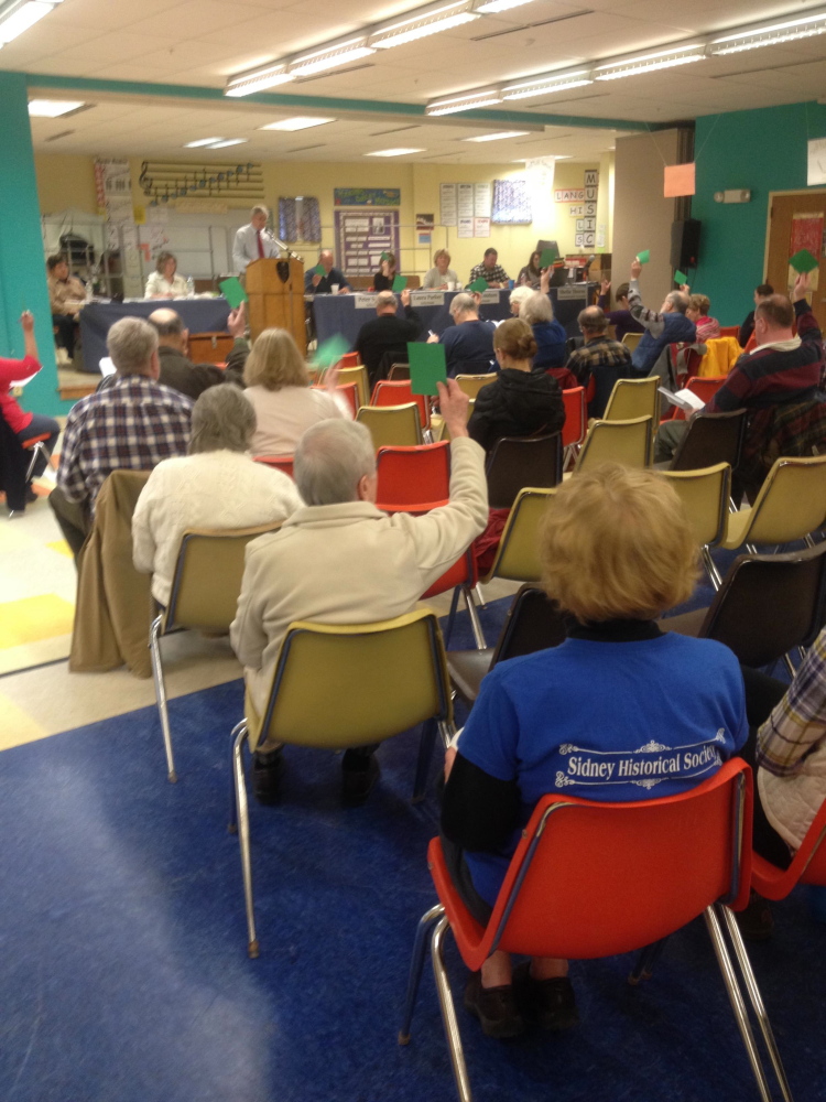 Sidney voters indicate their approval of an article with a show of green cards at Saturday’s annual Town Meeting.