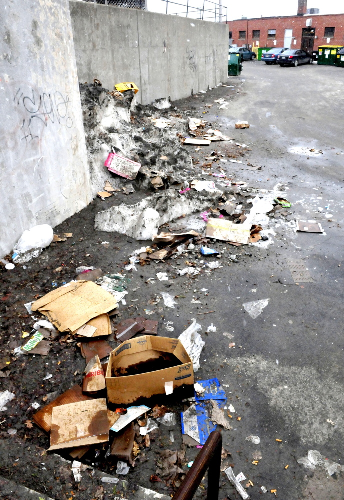 Piles of trash are scattered in an alley between an apartment building and businesses near the Concourse in Waterville on Monday. A public meeting is planned to consider repealing the pay-as-you-throw method of trash collection, which has been criticized as creating an incentive for illegal disposal of garbage.