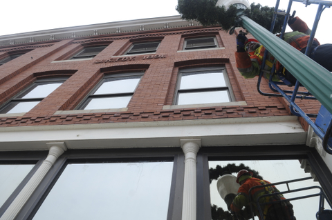 City of Gardiner employee Don Robideau removes a wreath on a pole next to the Bank of Maine branch on Water Street in Gardiner on Monday. Camden National Bank and The Bank of Maine announced a plan Monday to merge, which if successful would create a new bank that surpasses Bangor Savings Bank as the largest bank headquartered in Maine.  Formerly Gardiner Savings, Bank of Maine has had a presence in the community since the mid 19th Century. Staff photo by Andy Molloy