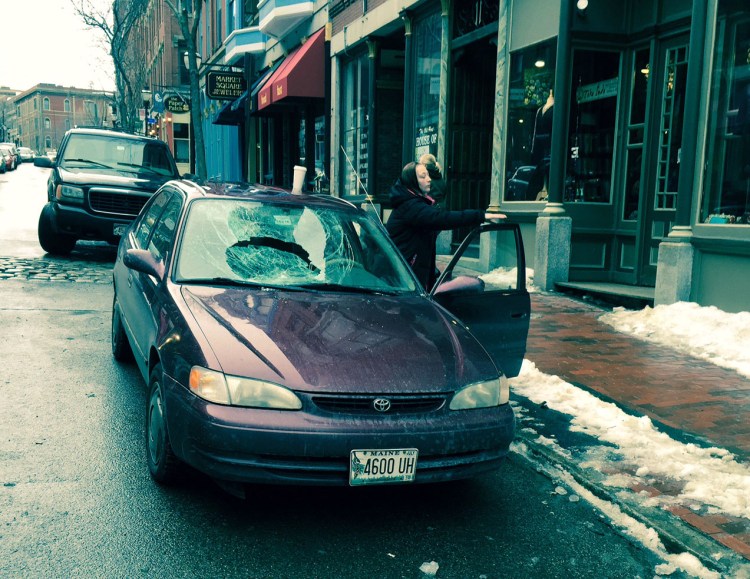 Kassie Grant removes items from her car after its windshield was shattered by falling ice Wednesday afternoon on Exchange Street. The car was later towed away.