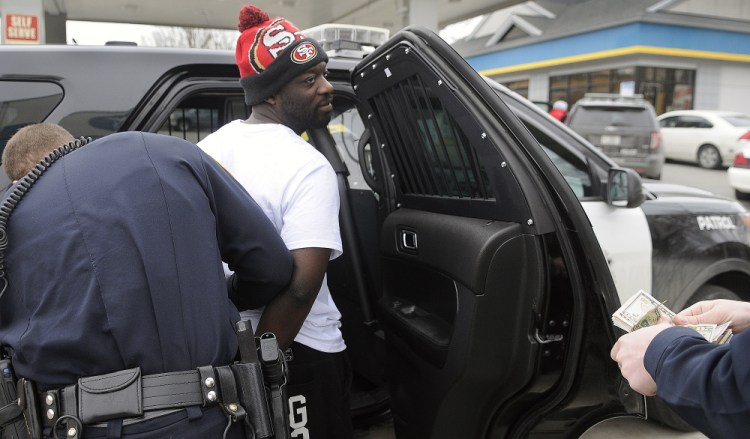 Augusta Police Officer Ben Murtiff, left, arrests Assama-vi Kuomou-Nete, 27, Wednesday as Officer Todd Nyberg counts money seized following his apprehension in Augusta. Police detained Kuomou-Nete after receiving reports of a man assaulting a female.