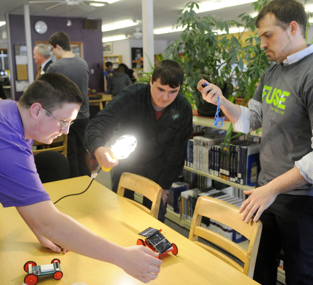 Gardiner Area High School teacher Justin Stewart times a solar car Monday that students Chris Wheeler, 14, left, and Cameron Cormier, 14, assembled as part of the green technology program at the school called FUSE. The FUSE program invites young people to explore hands-on challenges inspired by real-world design practices.