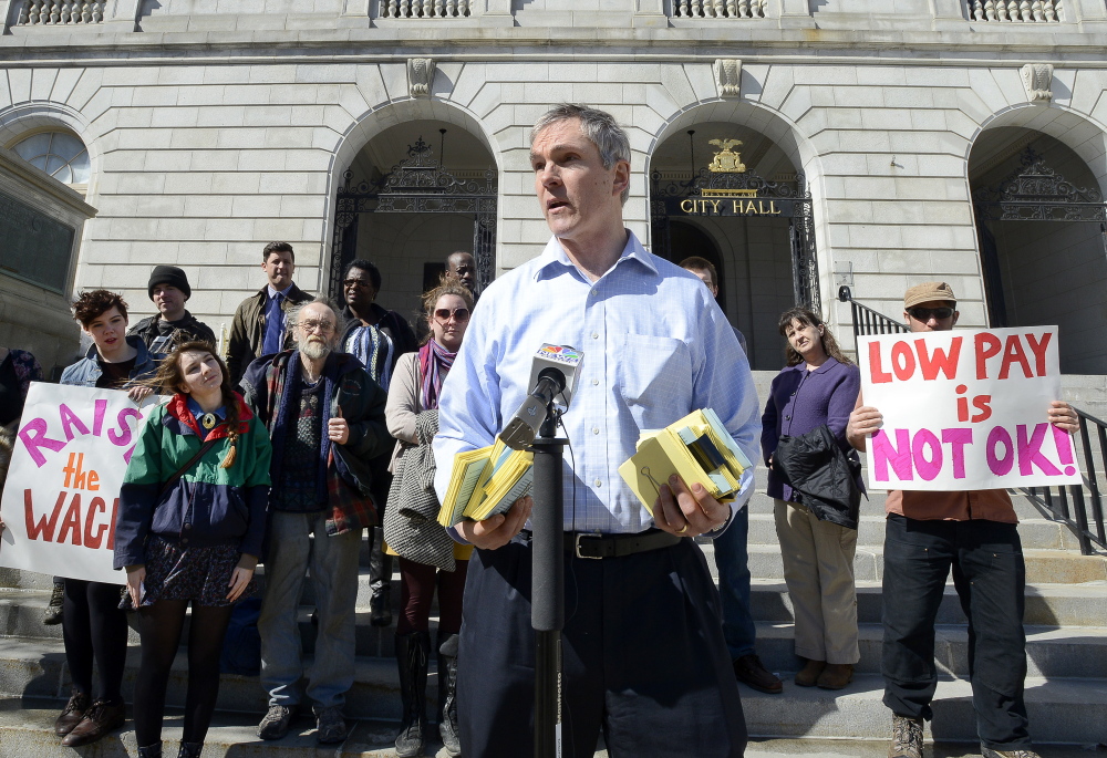 More than a dozen advocates gathered at Portland City Hall last month to deliver postcard petitions to City Councilor Jon Hinck, shown speaking, that asked for action on increasing the minimum wage.