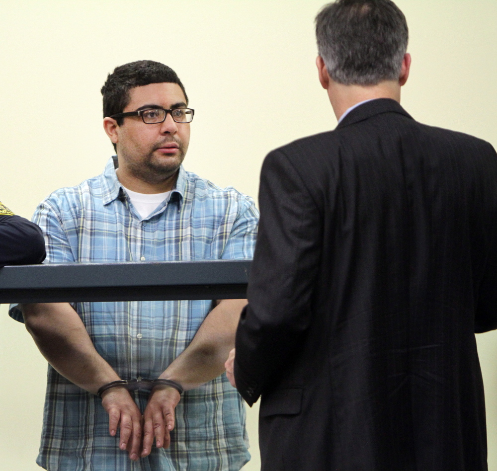 Carlos Colina Jr., left, speaks with his attorney John Cunha Jr. during his arraignment in Cambridge District Court in Medford, Mass., on Monday.