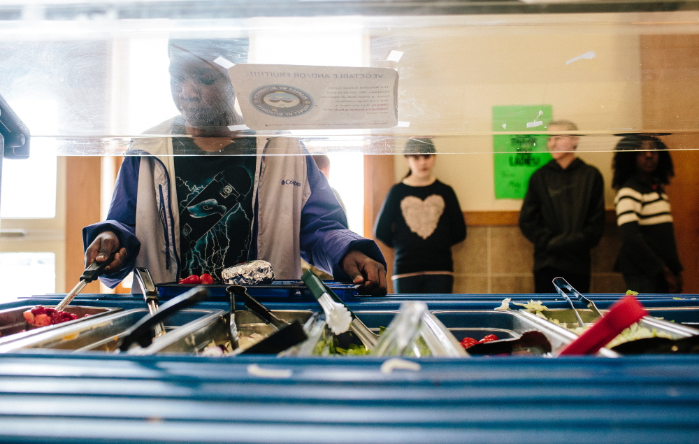 Fifth-grader Salem Bukasa, 10, spoons strawberries and pineapple onto his lunch tray last week at Westbrook Middle School. “I don’t really think that taking vegetables or fruit is a big deal. The days where they have bananas are my favorite,” Bukasa said.