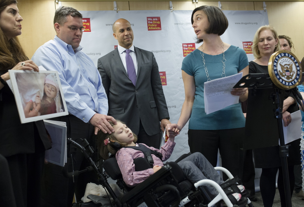Polly VanderWoude holds the hand of her daughter Olivia, who suffers from severe epilepsy, as she advocates for a law that would allow access to marijuana extracts.